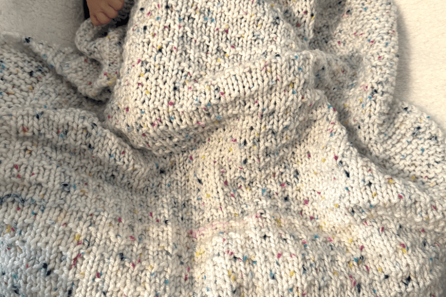 speckled hand knit blanket keeping baby warm